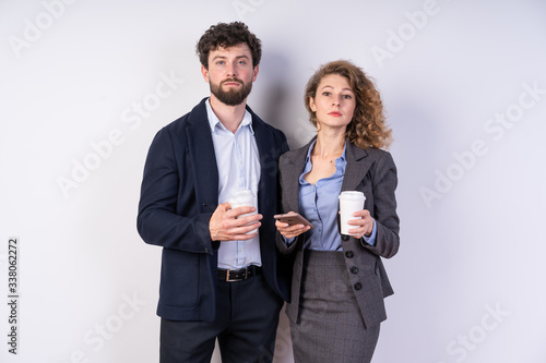 Business people drinking coffee together and at the same time communicate, keep the smartphone, looking right