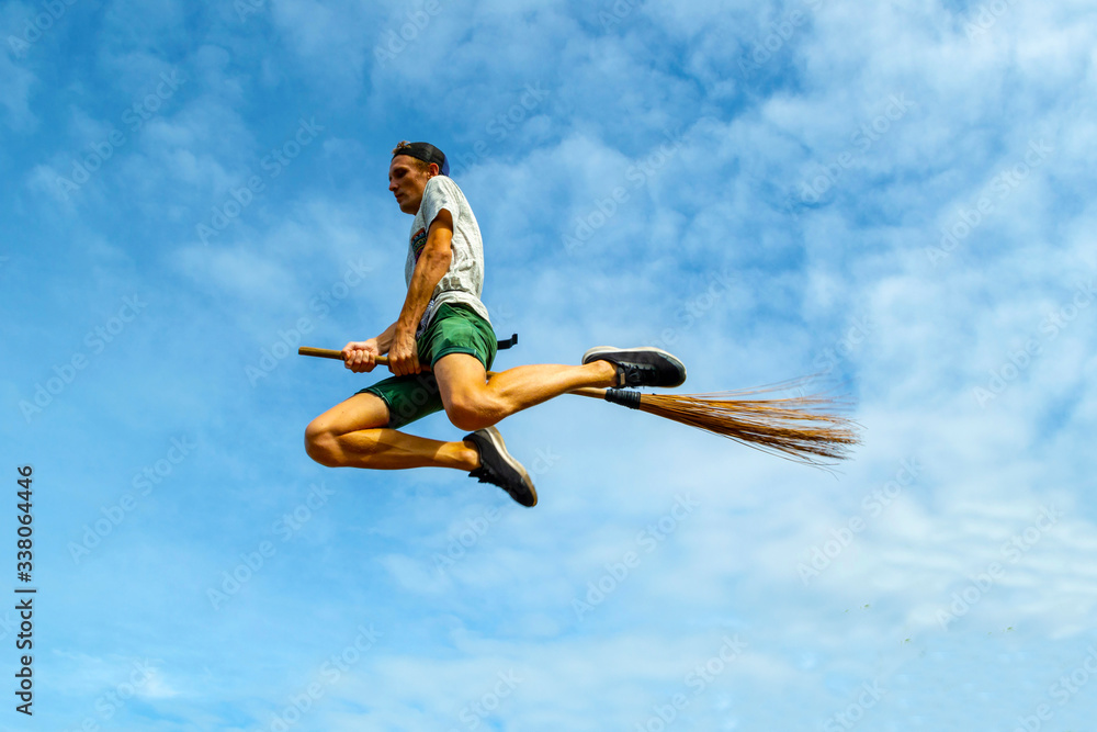 Young man flying on the broom in the blue sky of Siquijor Young man flying on the broom in the blue sky of Siquijor