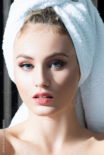 Close up portrait of woman posing wrapped in bathroom towels  Beauty portrait of a cheerful attractive half naked woman with a towel looking at camera.