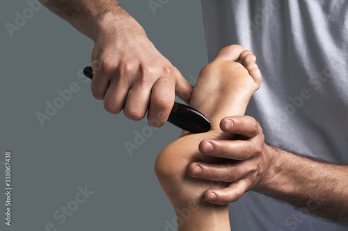 Billede på lærred Male masseur doing massage on beautiful naked woman body in the spa salon gua sha scraping acupuncture massage tool