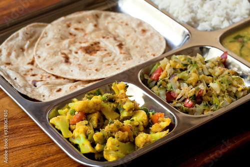 Selective focus on traditional food of India. Subji, bread chapati, vegetarian thali, daal, rice for customer of simple asian restaurant photo