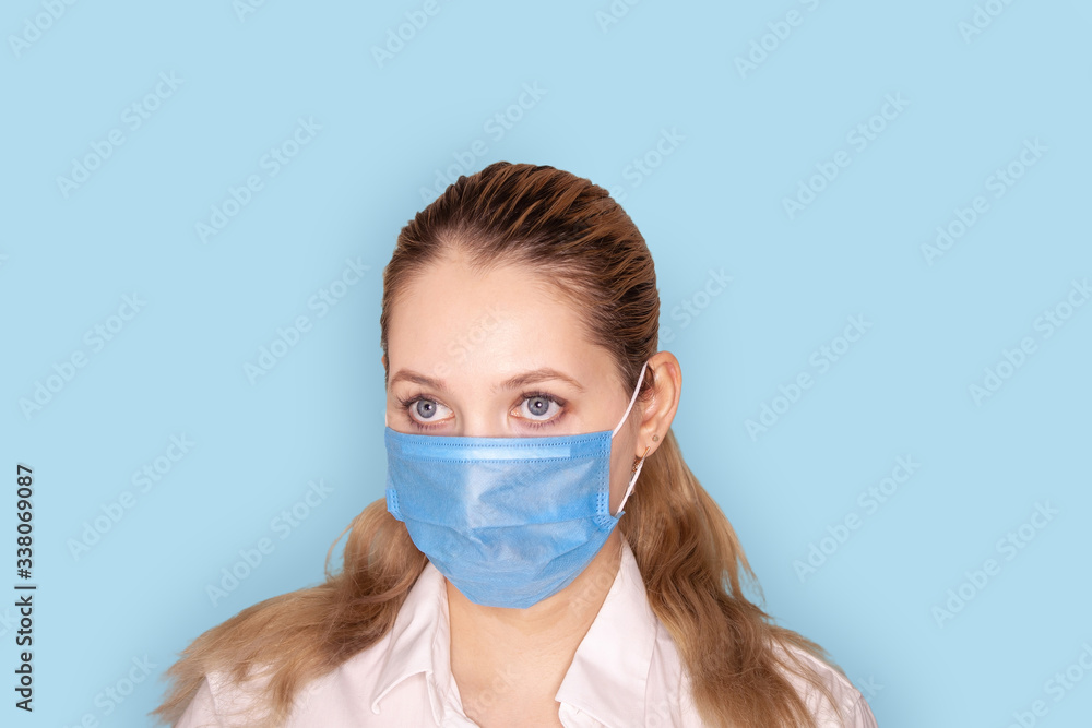 Young woman wearing blue medical mask isolated on blue background Young woman wearing blue medical mask isolated on blue background