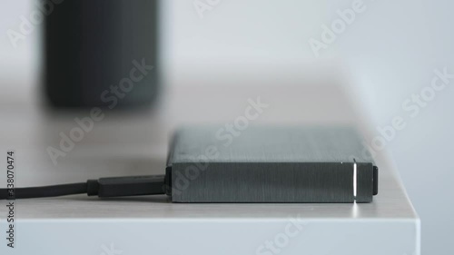 External Hard Drive On a Table, Led Light Flickering, Bluetooth Speaker in the Background - Solid Aluminium Casing HDD, Minimalist Design Composition - Macro Closeup photo