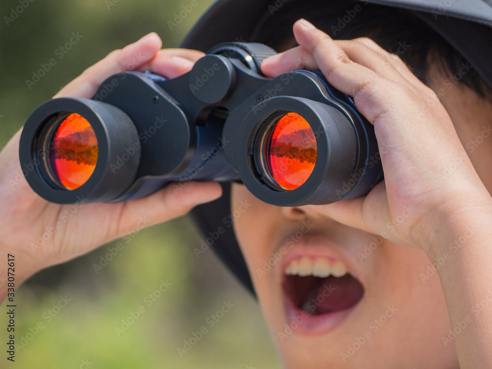 Young boy looking through binoculars on sunny summer day with happiness. Young boy looking through binoculars on sunny summer day with happiness.