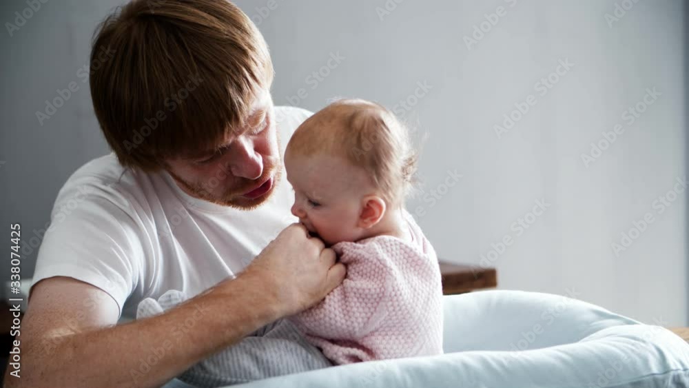 Excited dad training baby daughter to sit up. New father nursing little six month child at home. Medium shot. Baby care and parenthood concept Excited dad training baby daughter to sit up. New father nursing little six month child at home. Medium shot. Baby care and parenthood concept