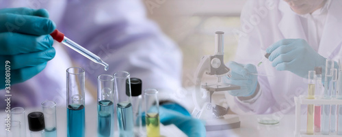 Laboratory concept; Scientist uses a dropper to transfer chemical reagent to test tube. He observes the chemical reaction with a blurred background of research in the laboratory