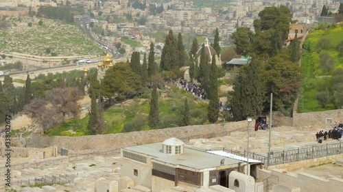 View of Christian tourists people walk by The Orthodox Church of Maria Magdalena on Mount of Olives of Jerusalem in Israel. Also the Dominus Flevit Church and the Zion Jewish Cemetery can be seen.