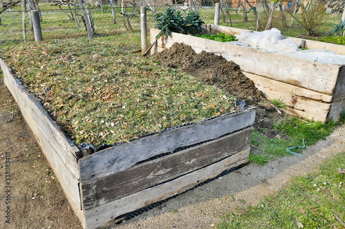 Stage of preparation of a raised garden bed with different layers of organic material - covered with pine needles