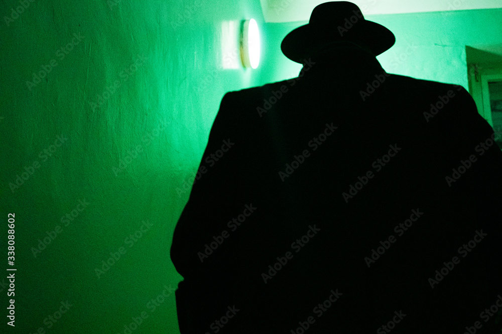 
Silhouette of a large man in a hat on a dark staircase