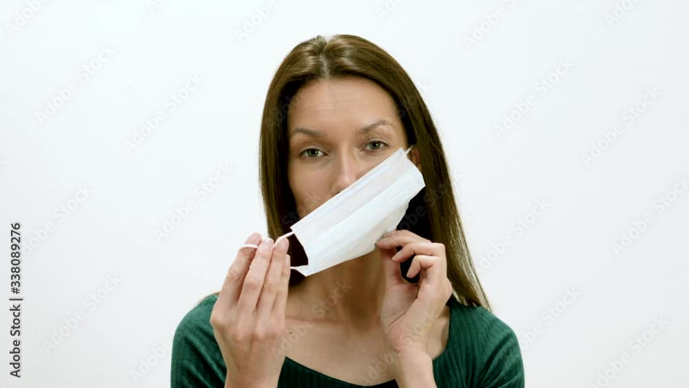Close up of a beautiful young woman wearing protective mask and looking at camera on a white background. Healthcare or medical concept for safe life. 4K Close up of a beautiful young woman wearing protective mask and looking at camera on a white background. Healthcare or medical concept for safe life. 4K