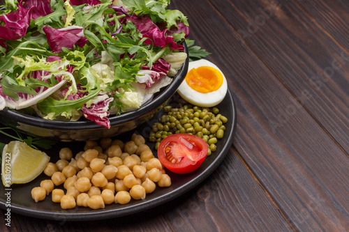 Chickpea, mung bean, multicolored leafy vegetable mix in black plate.