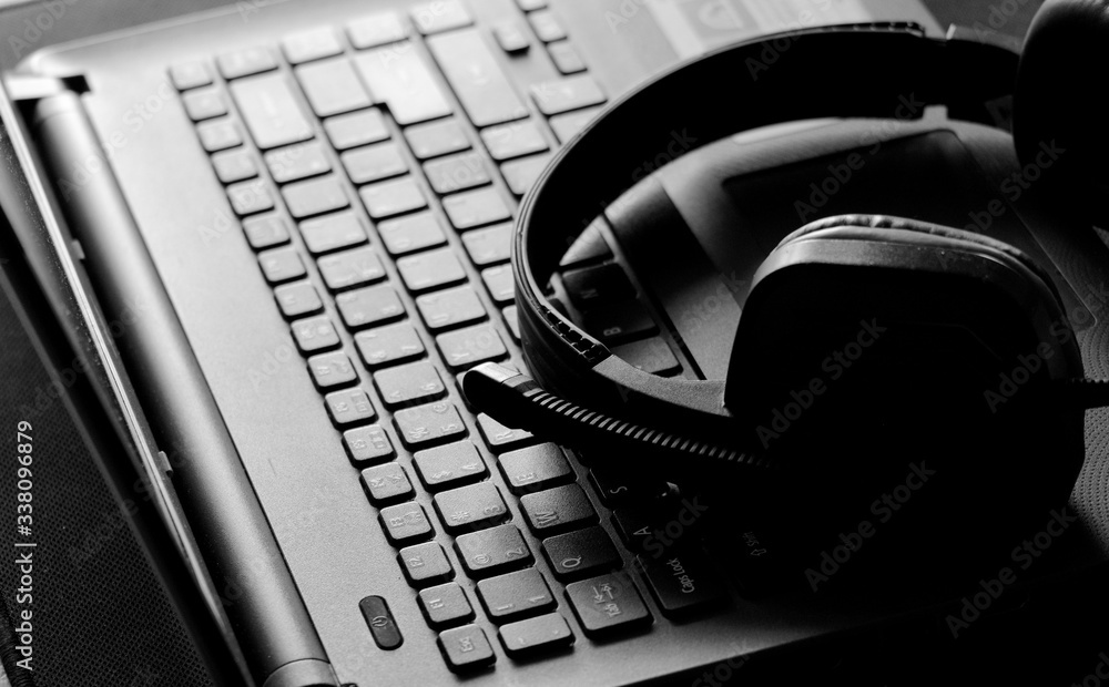 gaming headphone laying on the laptop keyboard, monochrome image of laptop on table
