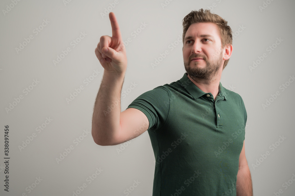 Fototapeta premium Portrait of serious stylish attractive man with thick beard, dressed in casual green t shirt using touchscreen