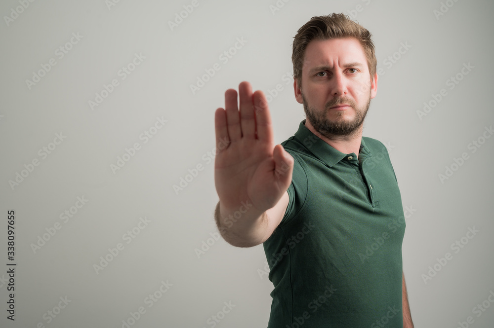 Portrait of serious stylish attractive man with thick beard, dressed in casual green t shirt showing stop gesture Portrait of serious stylish attractive man with thick beard, dressed in casual green t shirt showing stop gesture
