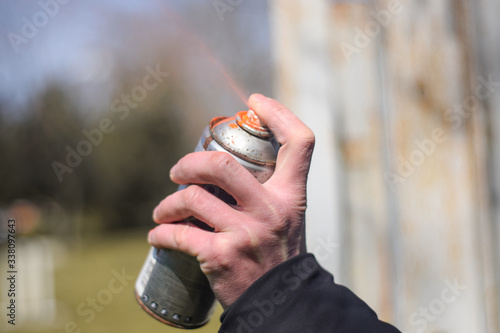 Spray paint close up. Spray paint in hand on outdoors. Orange spray paint can close up