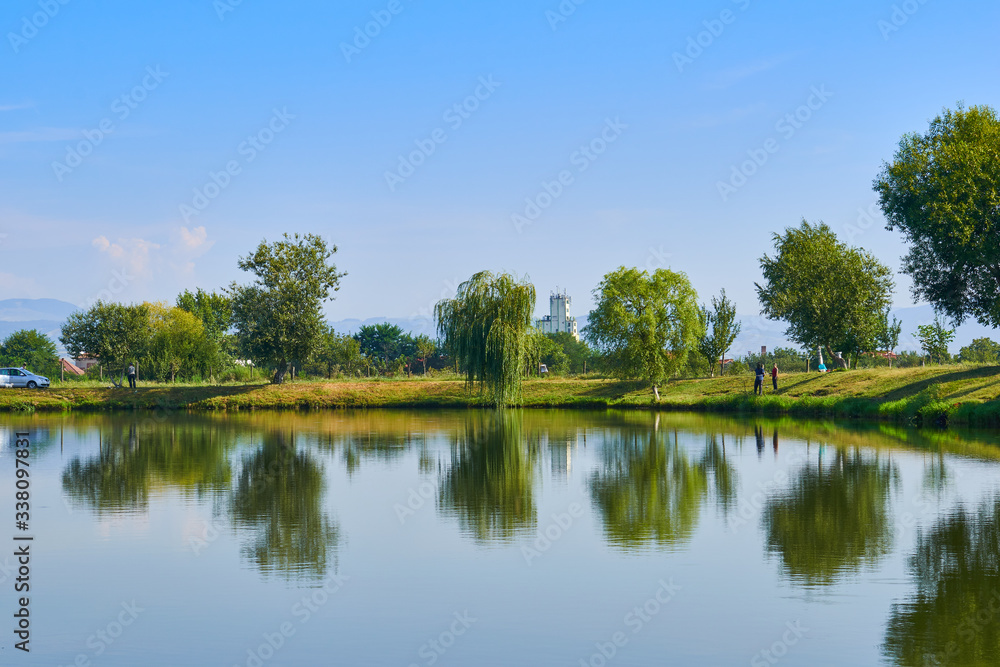 landscape with lake, trees and blue sky with clouds