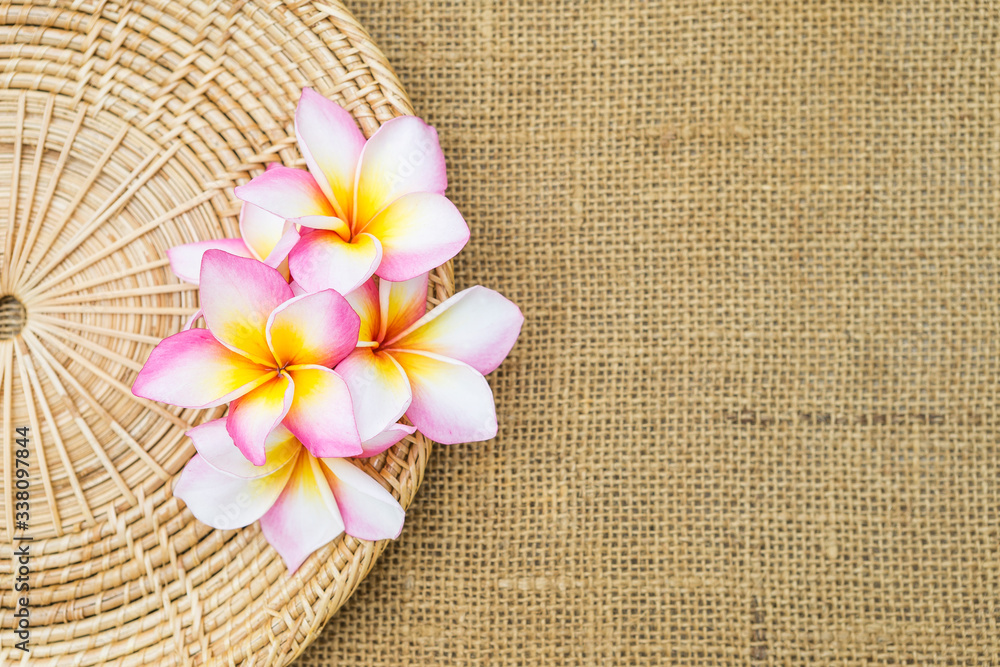 Beautiful colorful Plumeria flower on rattan tray with space on hessian texture background Beautiful colorful Plumeria flower on rattan tray with space on hessian texture background