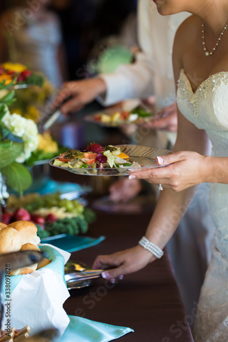 Bride and bridal party serving food on wedding day at buffet