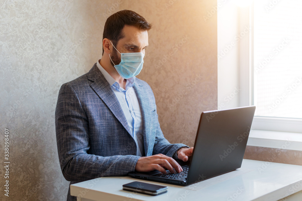 A man in a medical mask works on a laptop A man in a medical mask works on a laptop