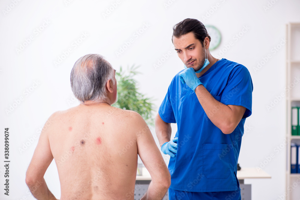 Fototapeta premium Old man visiting young male doctor dermatologist