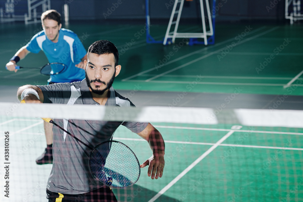Multi-ethnic pair of badminton players taking part in competition