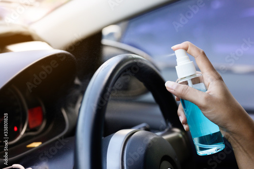 Hand of driver is spraying alcohol,disinfectant spray in car,safety,prevent infection of Covid 19 virus,coronavirus, contamination of germs or bacteria. Alcohol Sanitizer,Hygiene concept.