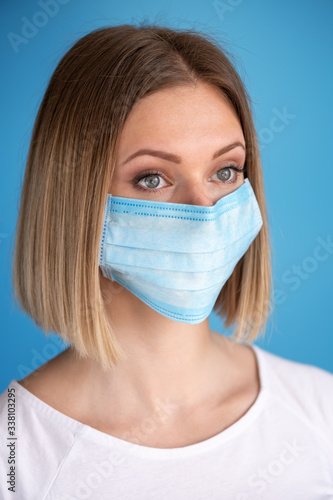 Nurse or doctor with face mask. Close up portrait of young caucasian woman model on blue background © byrdyak