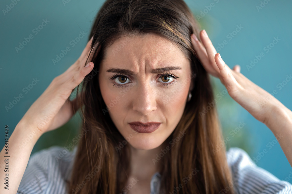 Frustrated young woman with headache and frowning while looking at camera at home. Frustrated young woman with headache and frowning while looking at camera at home.