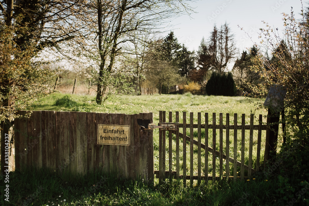 Hölzernes Gartentor mit Verbotsschild vor einem Garten im Frühling 