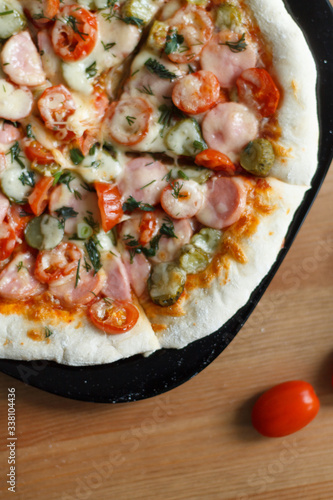 homemade pizza with sausage and cherry tomatoes close-up on a wooden table. culinary concept