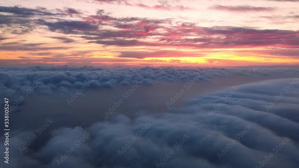 descending to the clouds with a sea beneath it and a colorful sunset above the horizon descending to the clouds with a sea beneath it and a colorful sunset above the horizon