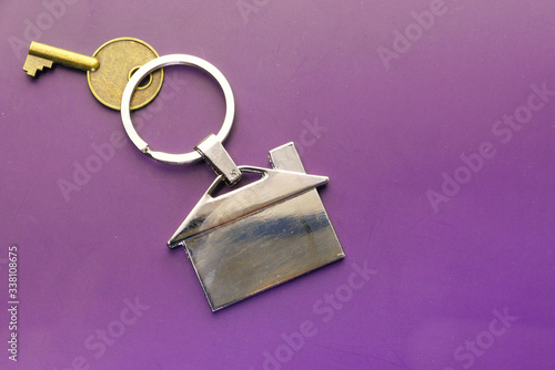 House keys with house shaped key chain on color background