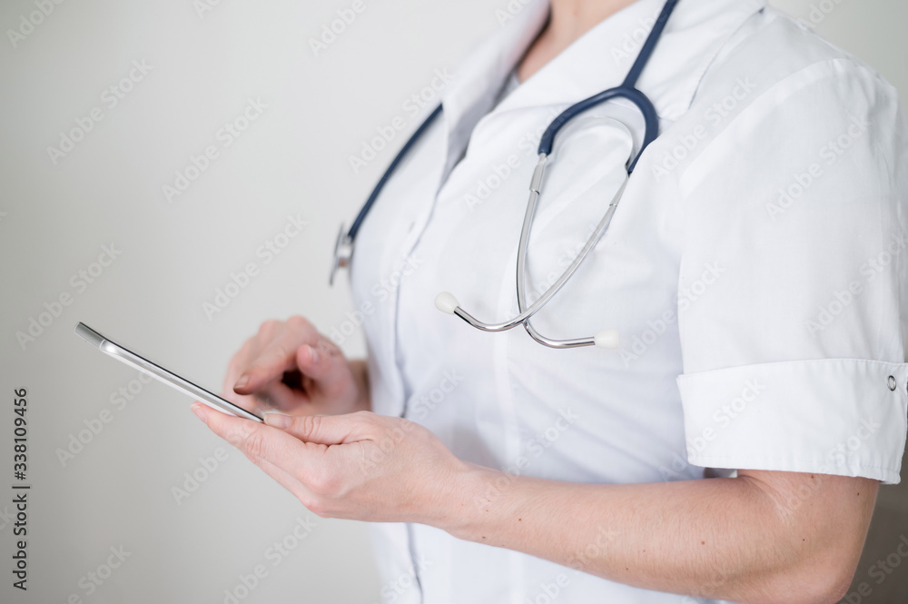 Unrecognizable female doctor uses cell phone. The medical worker communicates with patients on a smartphone. Cropped. Unrecognizable female doctor uses cell phone. The medical worker communicates with patients on a smartphone. Cropped.