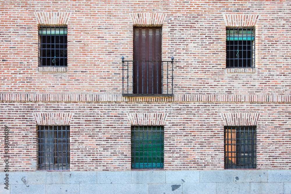 brick facade with five windows a balcony in a building in Madrid. Spain