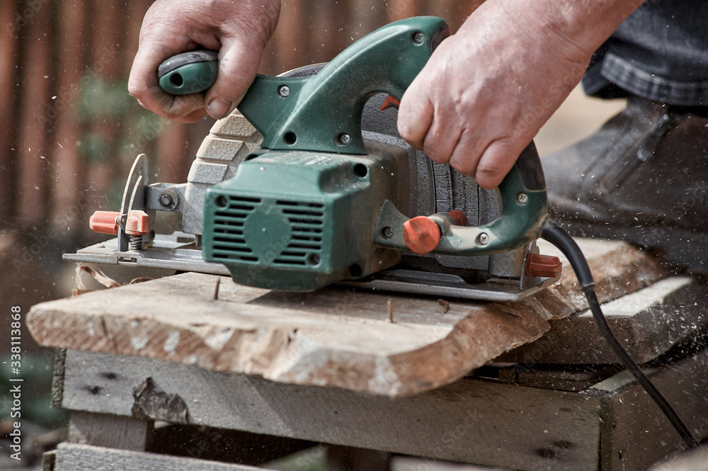 a hand circular saw cuts a board