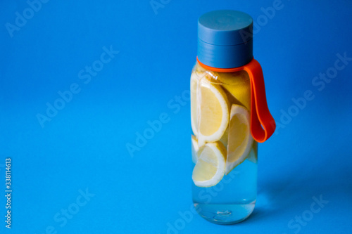 flat lay style concept of healthy lifestyle, sport and fitness at home. Bottle of water with lemons on blue background