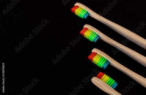 Pride. Group of rainbow eco bamboo toothbrushes  on black background. Top view  copy space. Natural organic product for oral hygiene. Dental zero waste and no plastic concept.