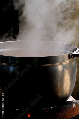 White smoke from a hot cooking pot in kitchen area with dark background 