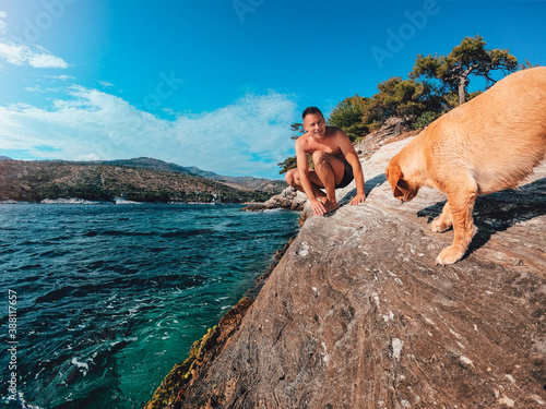 Men and his dog having fun on the rocky shore by the sea © kerkezz