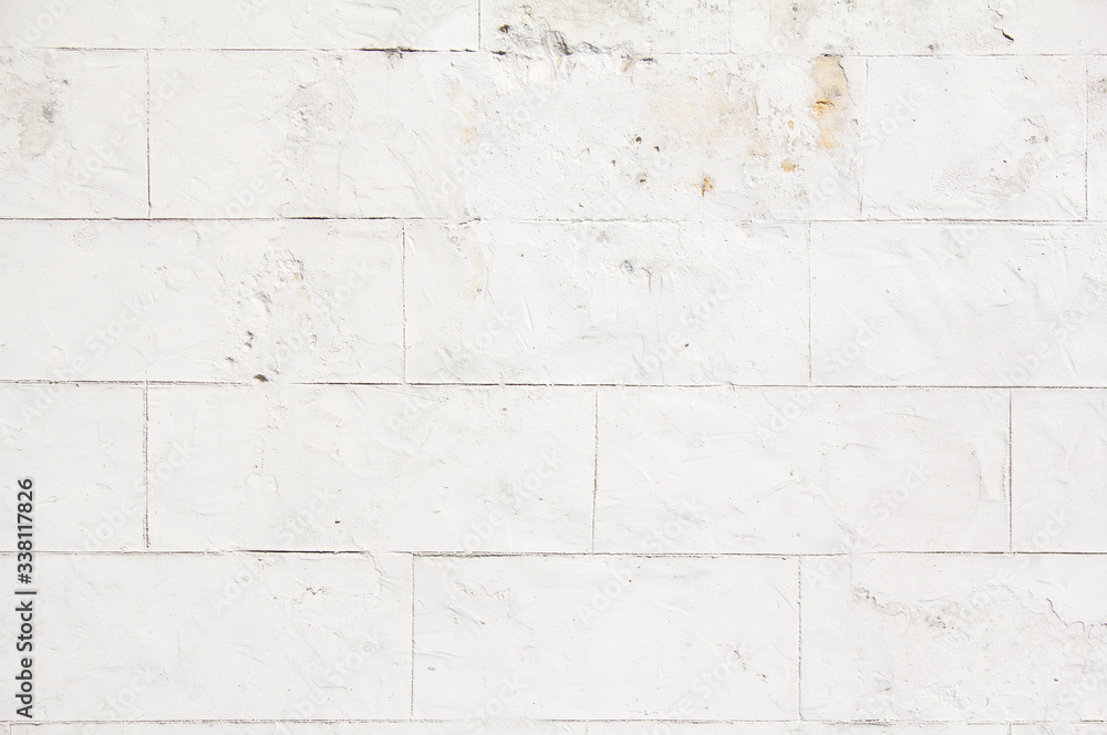 Naklejka premium Old white stone wall with dirty spots and stains and peeling paint texture background.