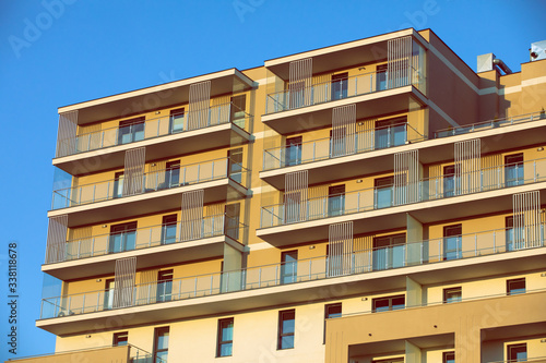 A high multi-family apartment block against a blue sky.