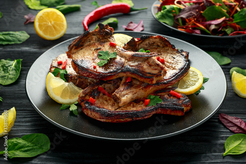 Homemade Grilled Pork loin chops in lemon sauce with herbs on rustic wooden table