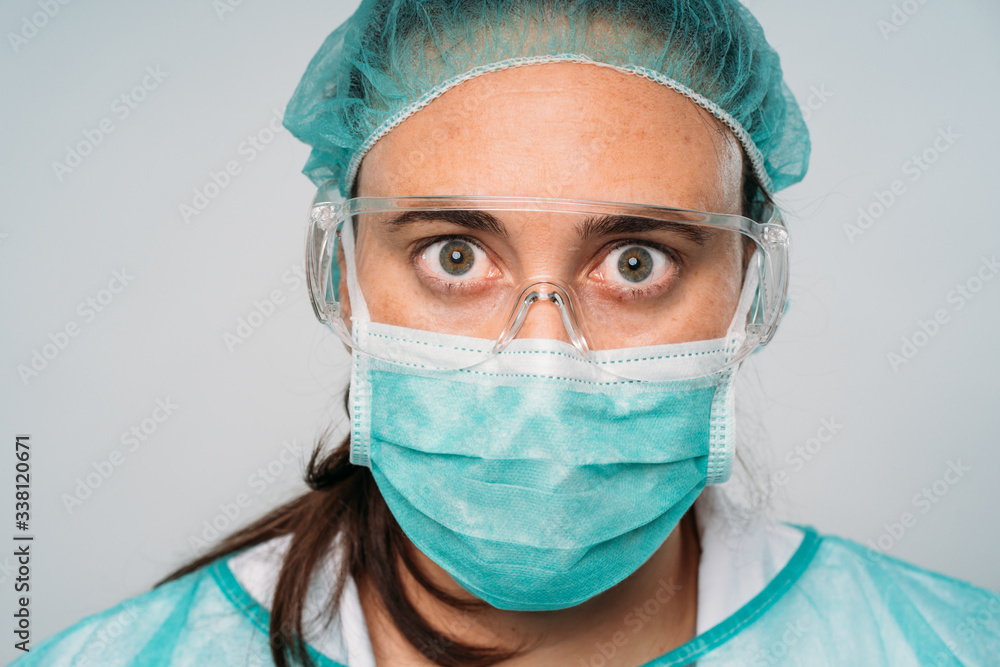 Close up of a Young woman doctor wearing medical mask, glasses, latex gloves and protective clothing against the virus on white background. COVID-19 The coronavirus pandemic. Close up of a Young woman doctor wearing medical mask, glasses, latex gloves and protective clothing against the virus on white background. COVID-19 The coronavirus pandemic.