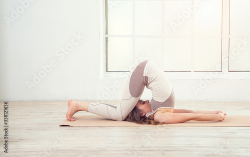 Pilates woman. Woman doing yoga exercises on mat in gym. Woman in the window background. Space for text. Woman exercising fitness in gym near the window.