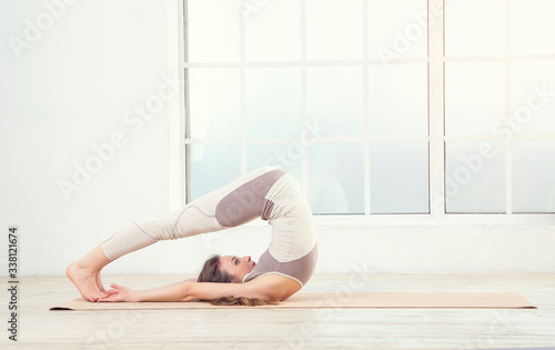 Pilates woman. Woman doing yoga exercises on mat in gym. Woman in the window background. Space for text. Woman exercising fitness in gym near the window.