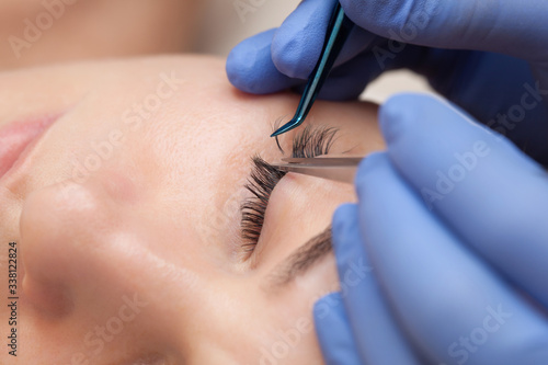 Eyelash extension procedure close up. Beautiful woman with long eyelashes in a beauty salon. Makeup concept