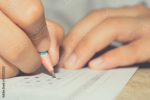 Test exam concept, pencil writing answer on paper answer of question in examination test. It assessment intended to measure knowledge, skill, aptitude, physical fitness, or classification students photo