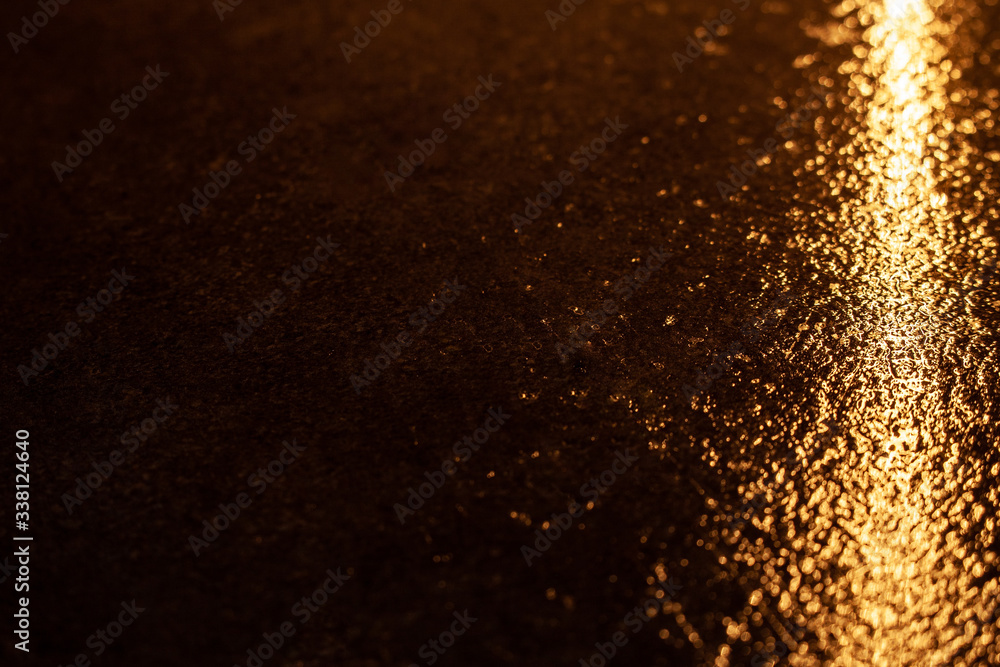 Abstract photo reflection of light on a wet surface. yellow neon light on a textured wet surface. Reflection of lights on the pavement. Abstract photo reflection of light on a wet surface. yellow neon light on a textured wet surface. Reflection of lights on the pavement.