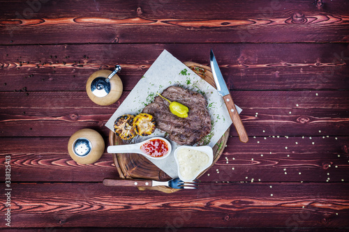 Delicious grilled steak with sauces and fried corn. There is a pepper grinder and cutlery. Top view