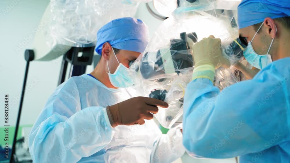 Neurosurgery with high-tech equipment. Two male surgeons working with medical microscope in a modern clinic. Medical concept. Neurosurgery with high-tech equipment. Two male surgeons working with medical microscope in a modern clinic. Medical concept.
